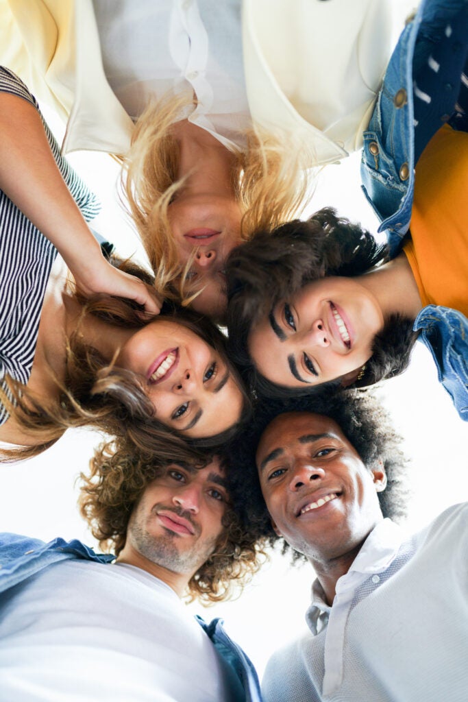 Multi-ethnic group of friends with their heads together in a circle outdoors