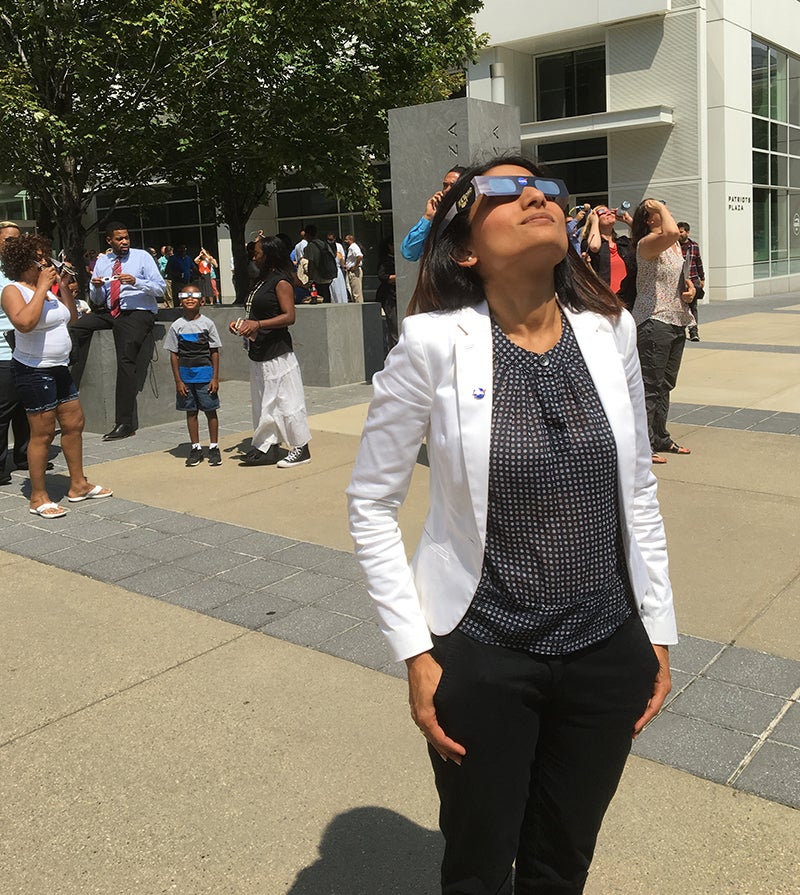 Participants outdoors wearing eclipse glasses looking up at the sun